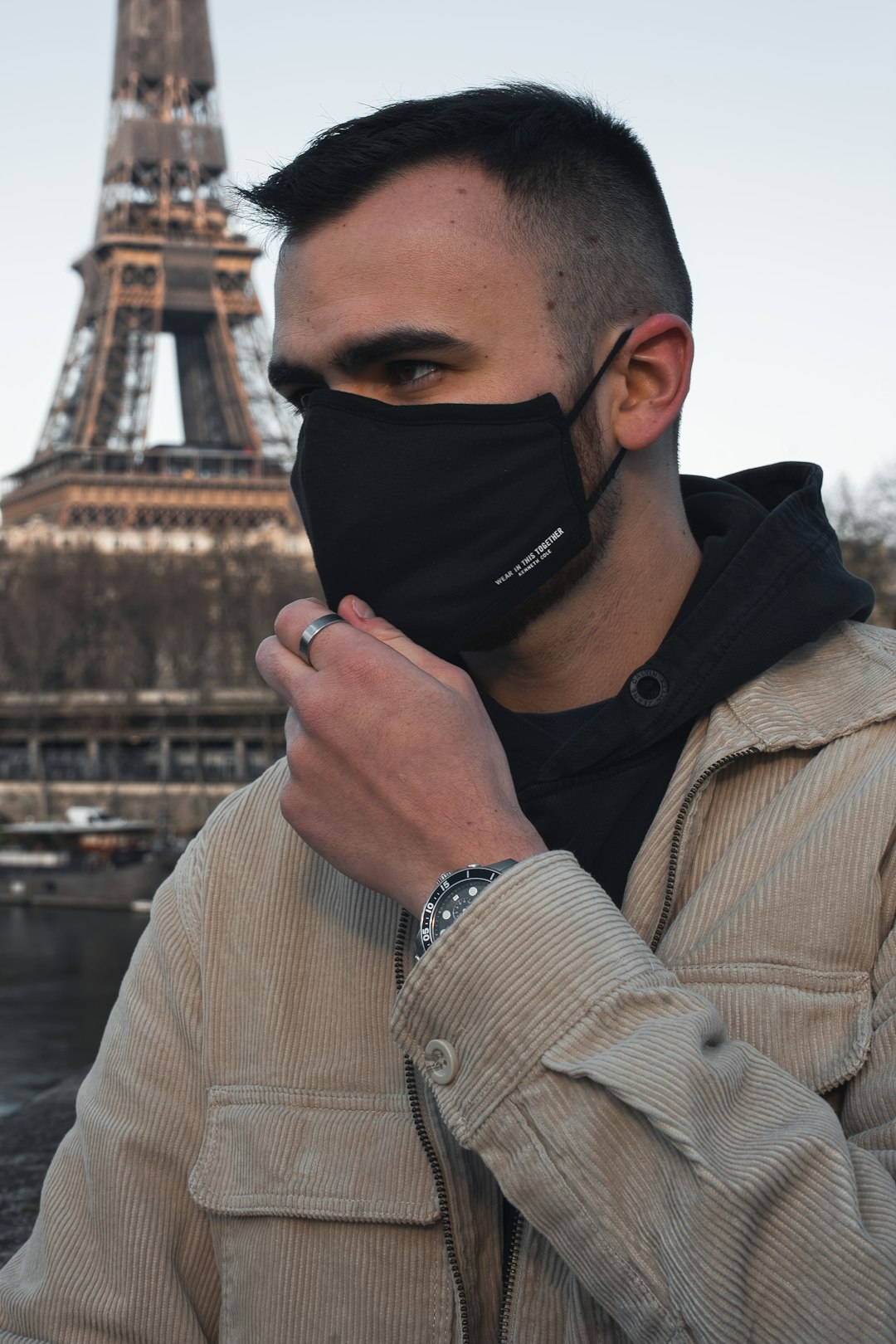 man in brown coat wearing black mask
