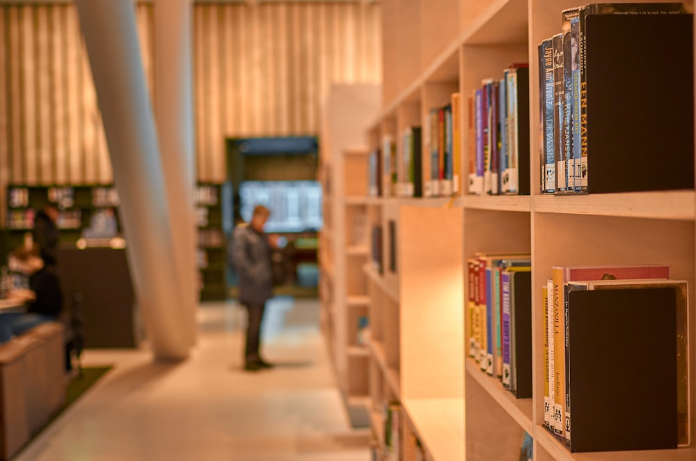 Hombre con chaqueta negra de pie cerca de estanterías de libros de madera marrón