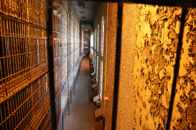 A dimly lit prison corridor with flickering fluorescent lights and peeling paint, evoking unease.