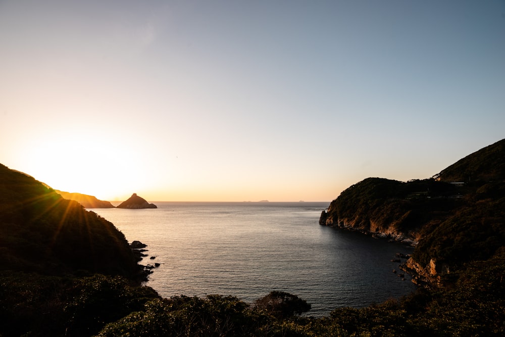 silhouette of mountain beside sea during sunset