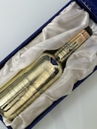 A golden-colored whisky bottle labeled 'Canadian Club' rests in a plush, white fabric lining within a navy blue box. The text 'IMPORTED' is prominently displayed on the bottle along with intricate details and a date noted as 1971.