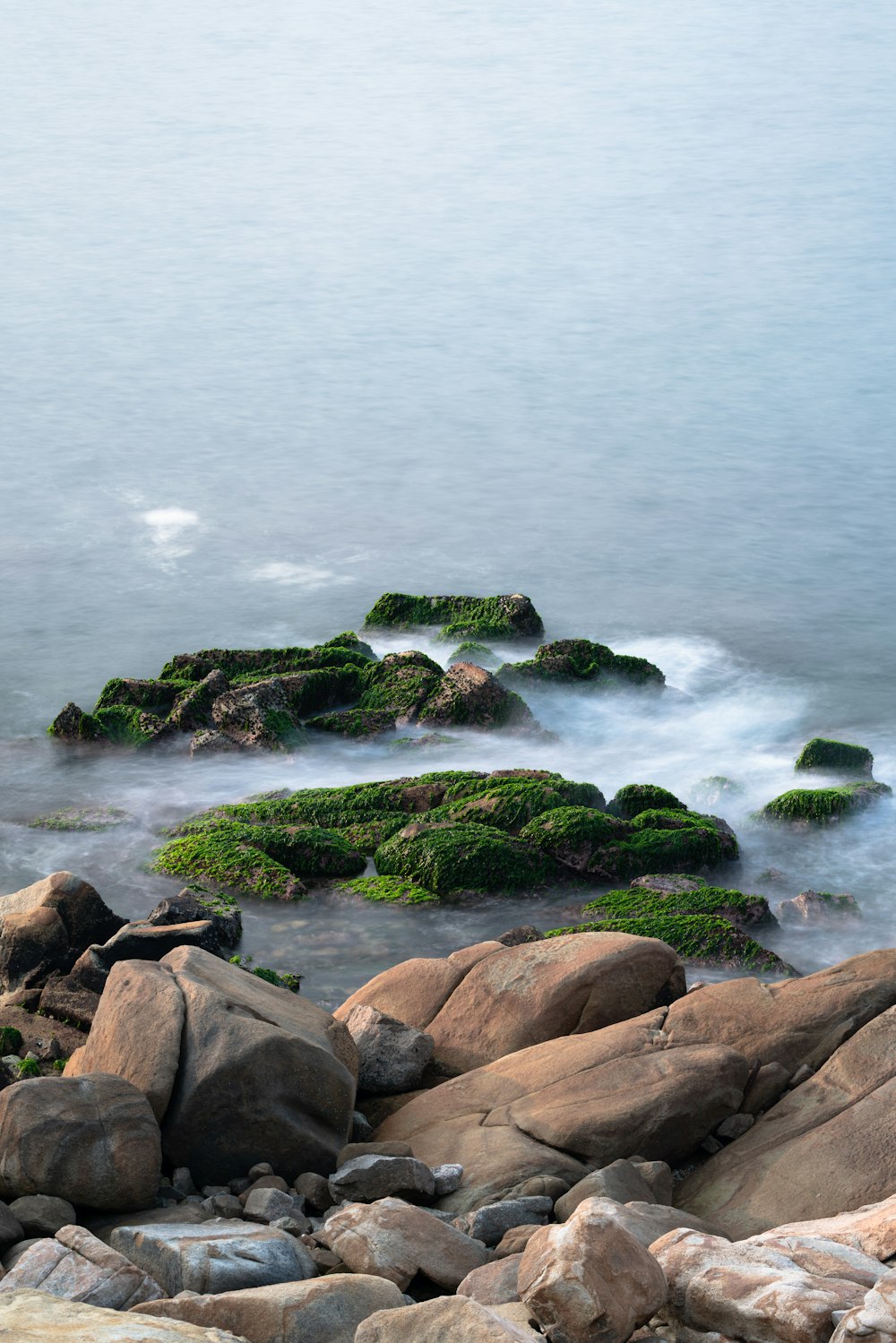 brown rocks on body of water during daytime