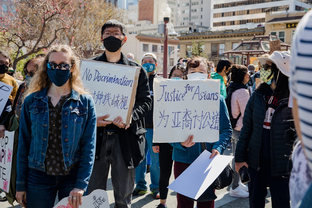 woman in blue denim jacket holding white and blue signage