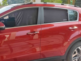 A friendly technician carefully replacing a windshield on a family SUV parked in a sunny driveway.