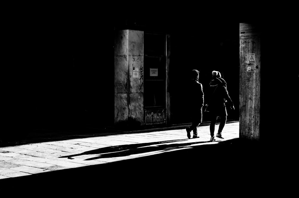 grayscale photo of 2 women walking on sidewalk