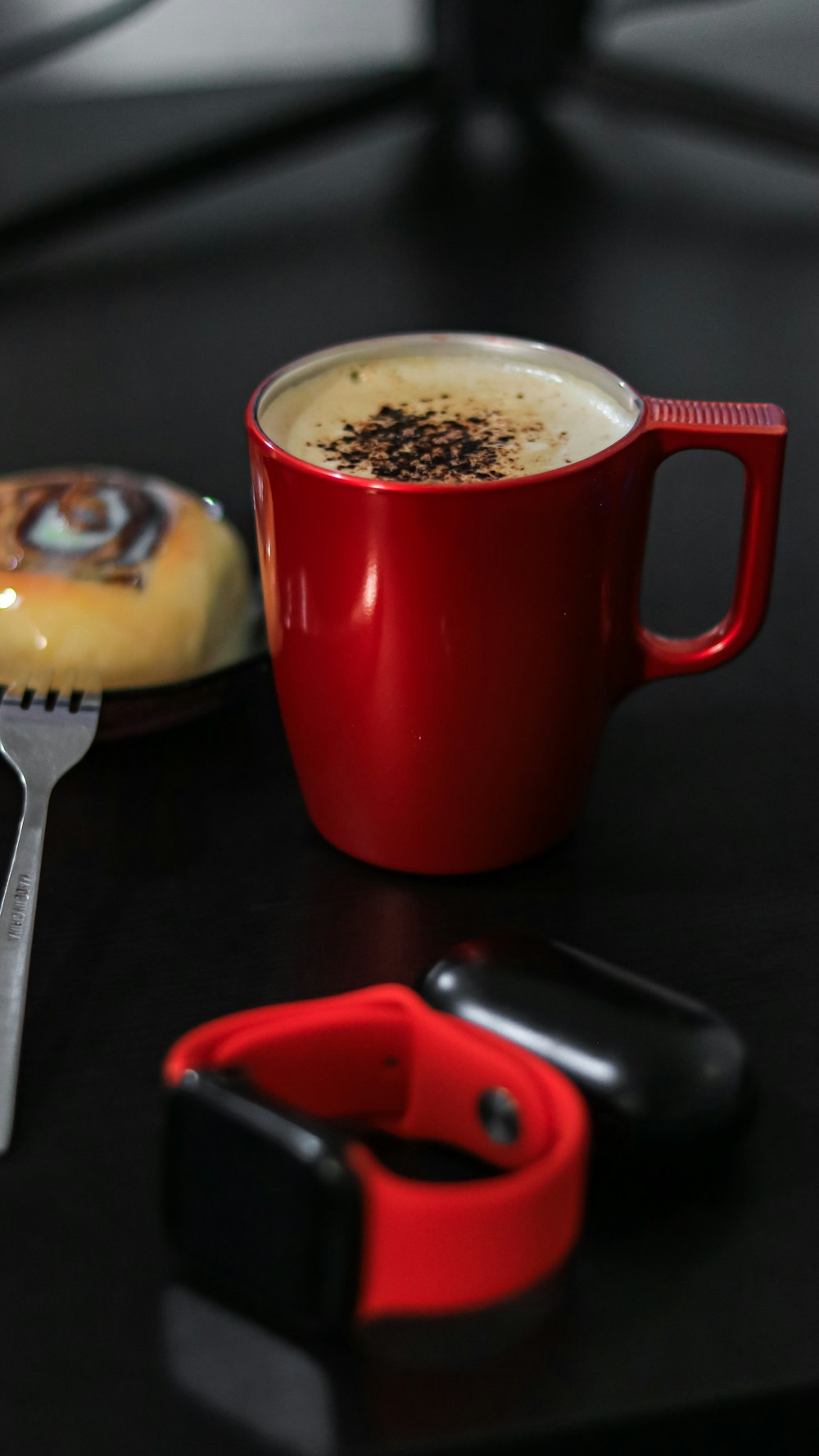 red ceramic mug beside silver fork