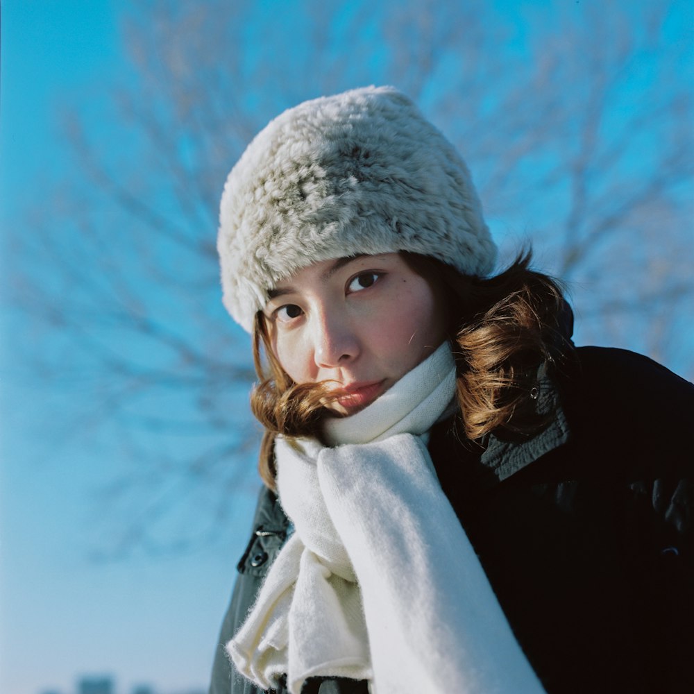 donna in cappotto invernale bianco e berretto in maglia grigia