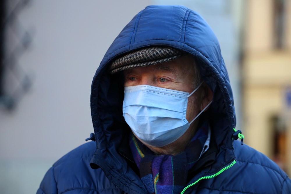 man in blue jacket wearing white face mask