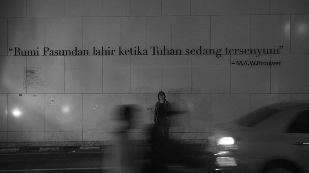 man in black jacket standing on sidewalk during night time