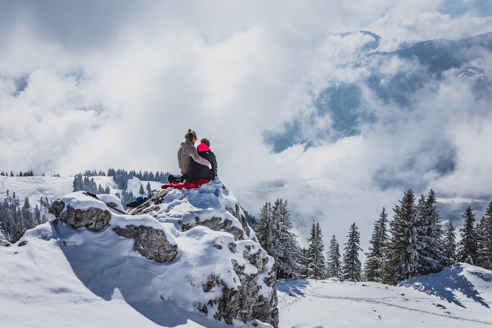 person in black jacket sitting on snow covered mountain during daytime