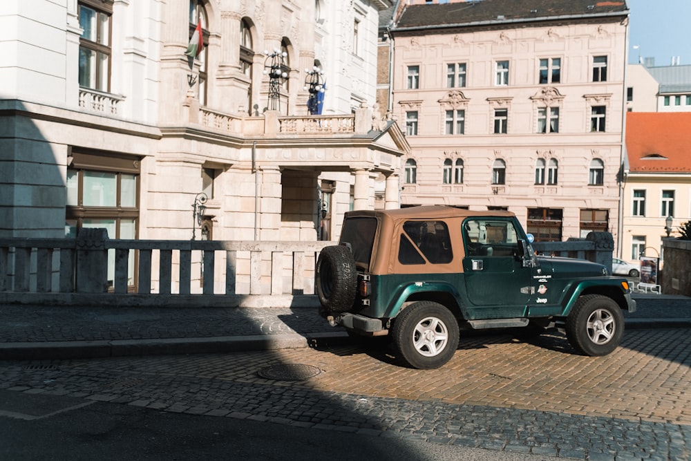 green suv parked beside beige concrete building during daytime