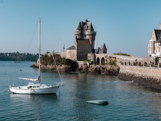 white boat on sea near brown concrete building during daytime