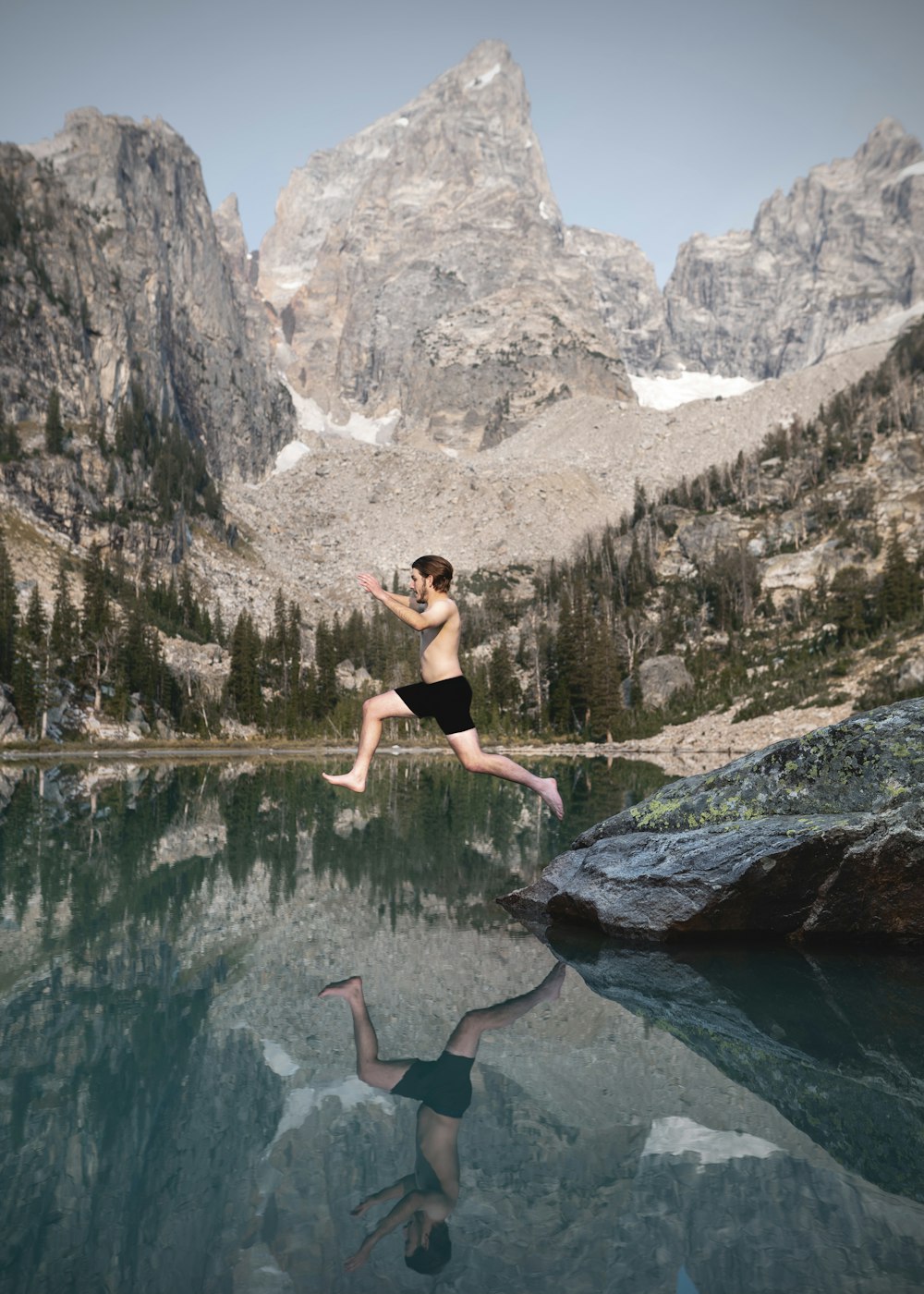 woman in black sports bra and black shorts sitting on rock near lake during daytime