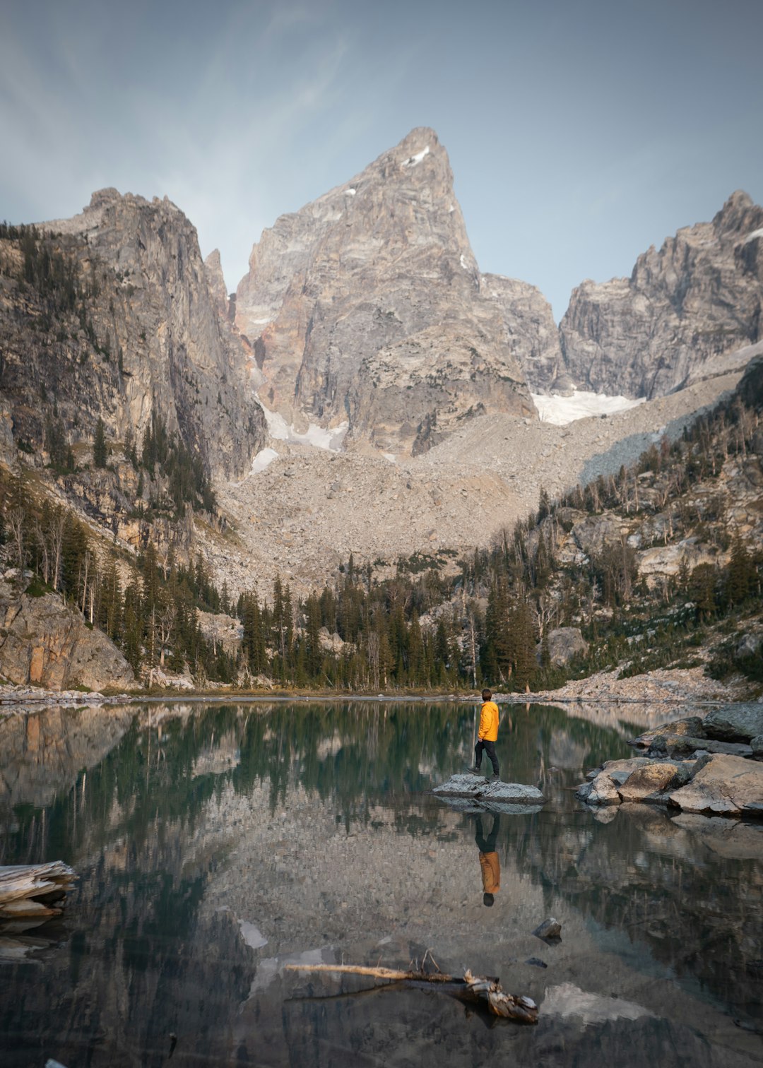 person in yellow jacket and black pants standing on boat on lake during daytime