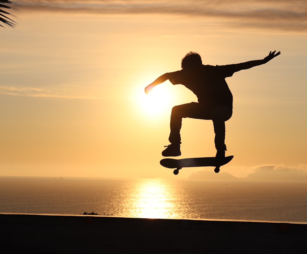 silhouette of man jumping on mid air during sunset