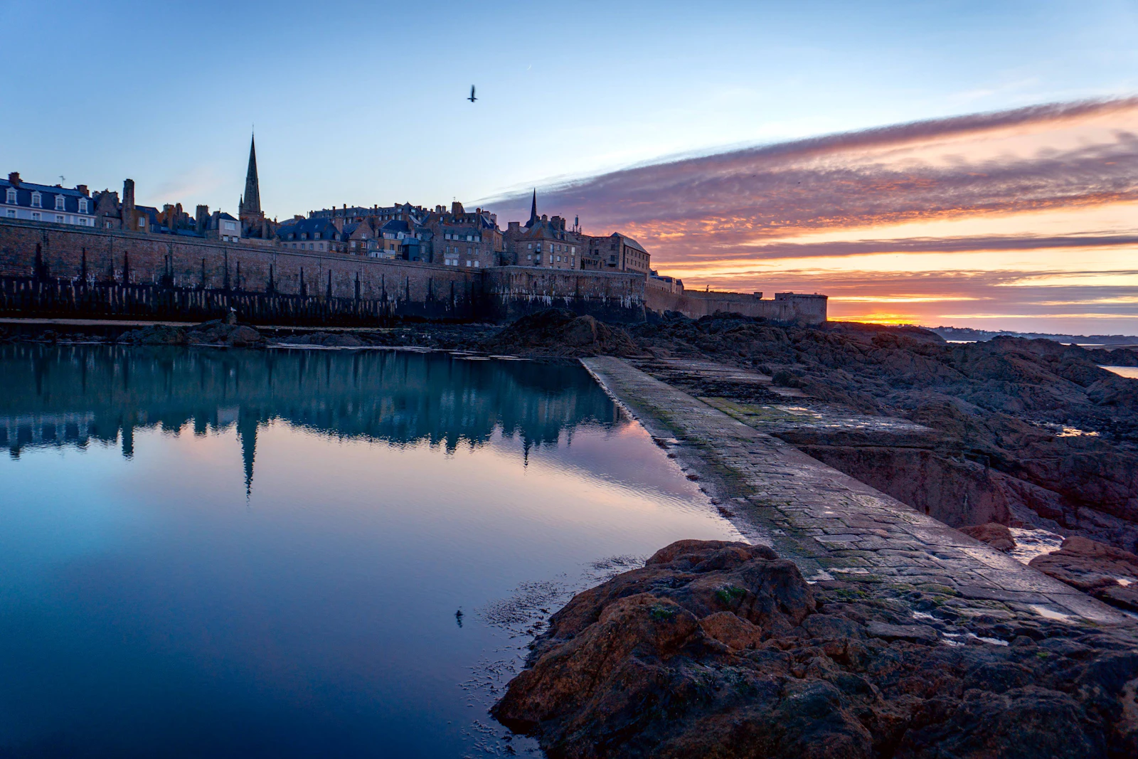 Saint-Malo intra-muros au lever du soleil, reflets dans le port — photo Maureen Cosnard / Unsplash