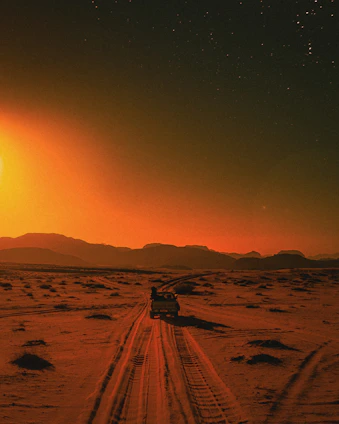 A comfortable, modern tourist van driving through the scenic Moroccan desert landscape at sunset.