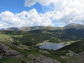 A scenic view highlighting Nina’s solo travel, with a suitcase by a mountain trail.
