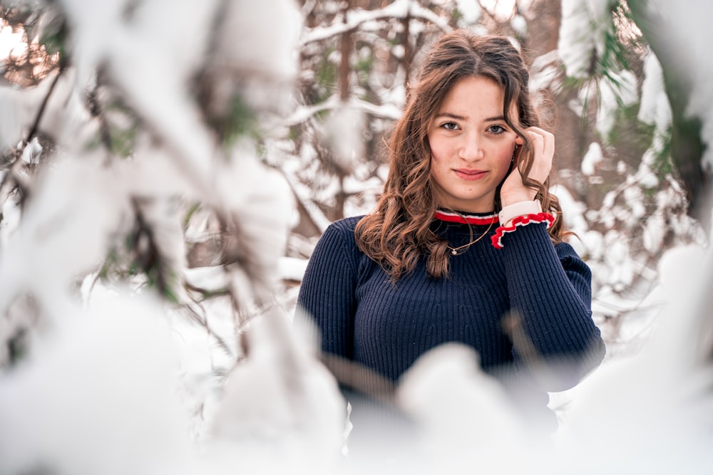 woman in blue sweater sitting on snow covered ground during daytime