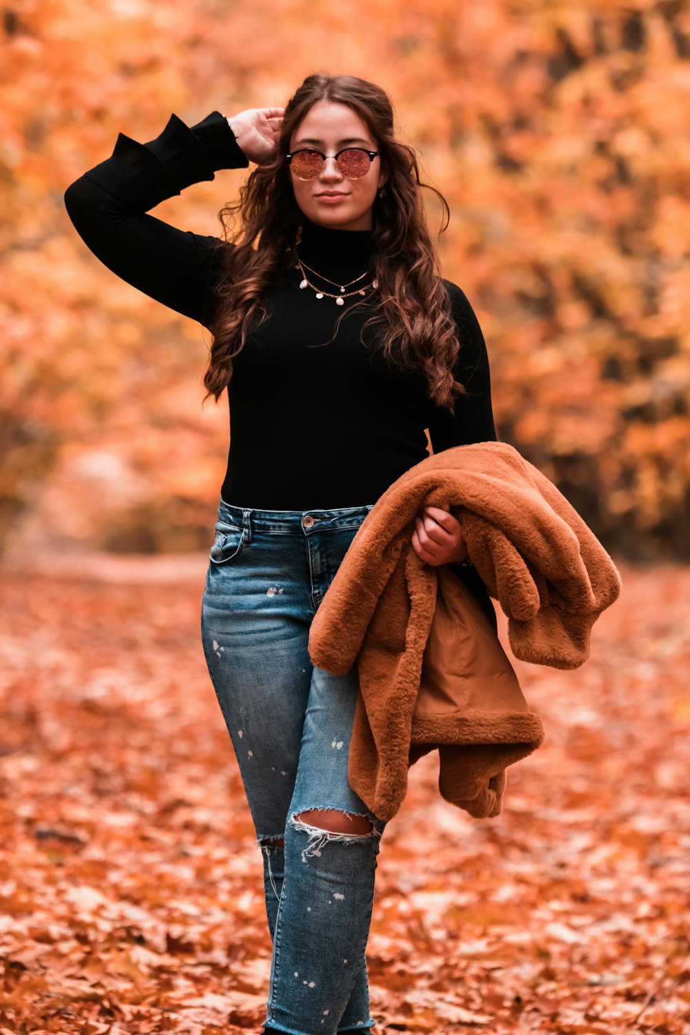 woman in black long sleeve shirt and blue denim jeans with brown scarf
