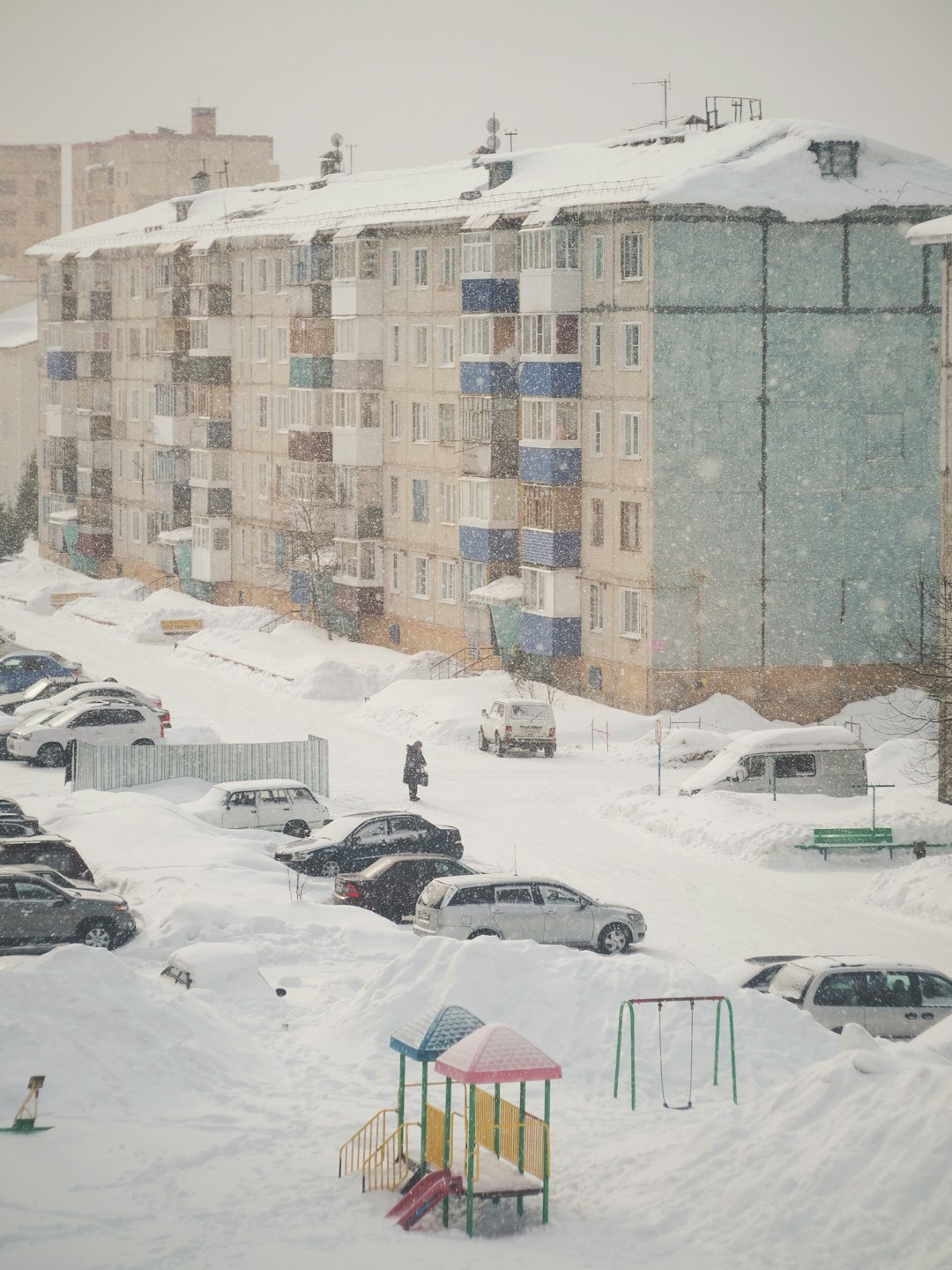 cars parked on snow covered ground near building during daytime