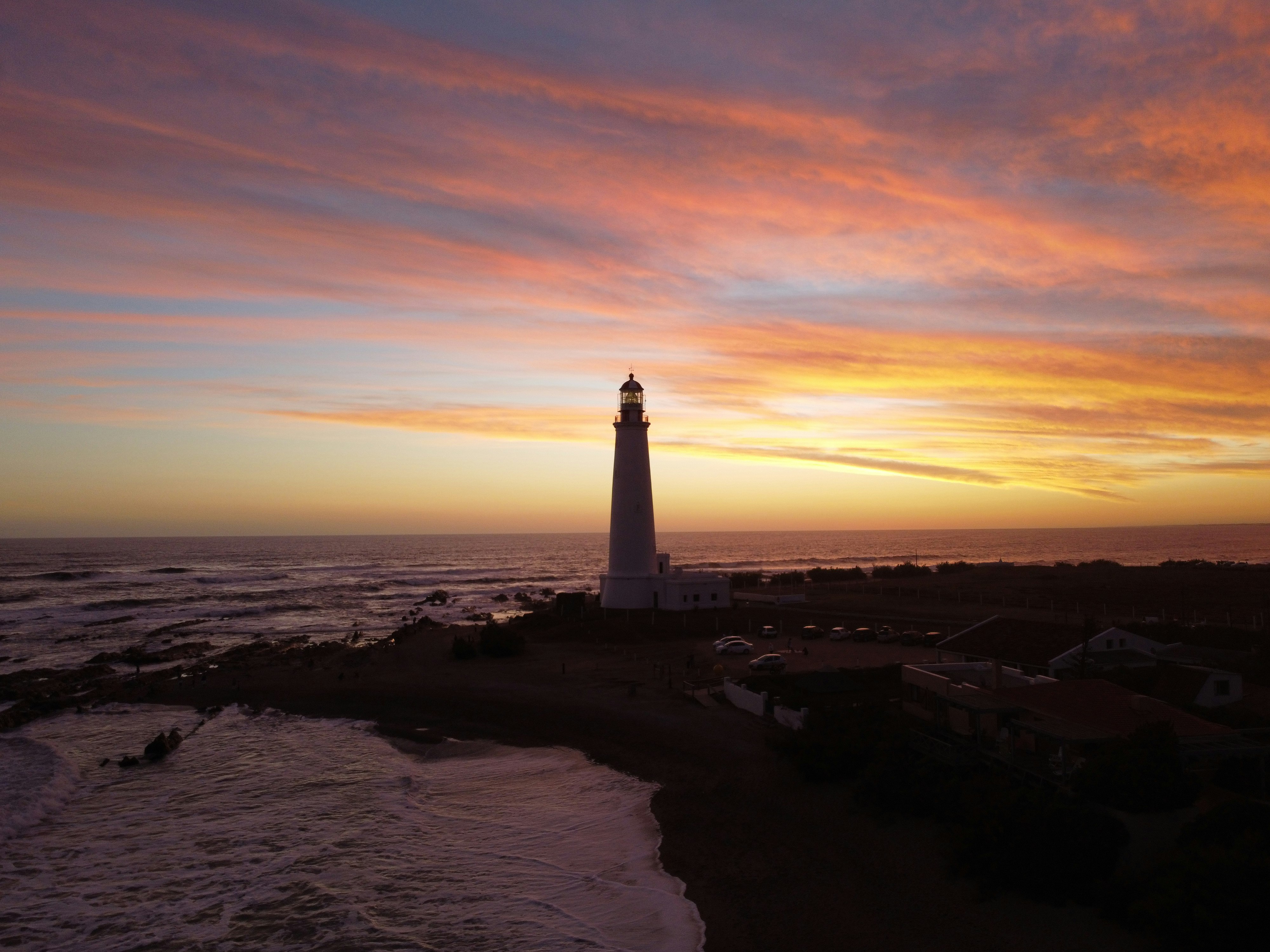 white and black lighthouse on brown sand during sunset