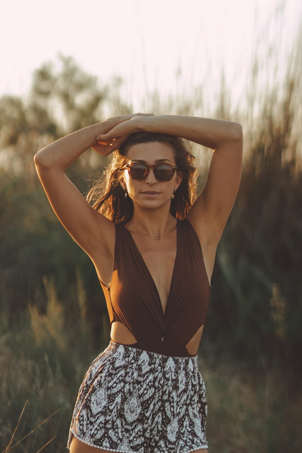 woman in black tank top and blue and white floral skirt wearing black sunglasses