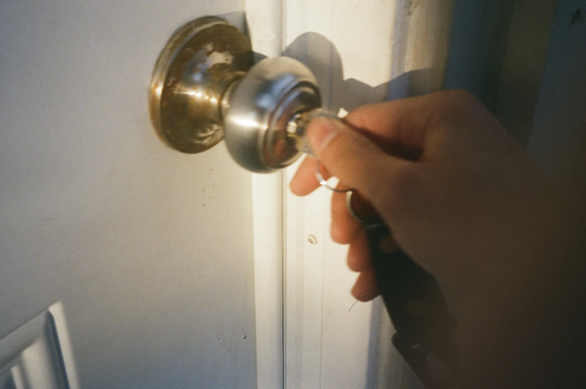 Worn brass knob lock being turned by hand