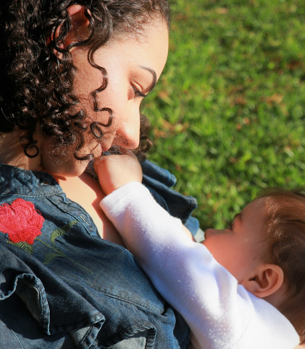 woman in blue and red floral shirt kissing girl in blue denim jacket