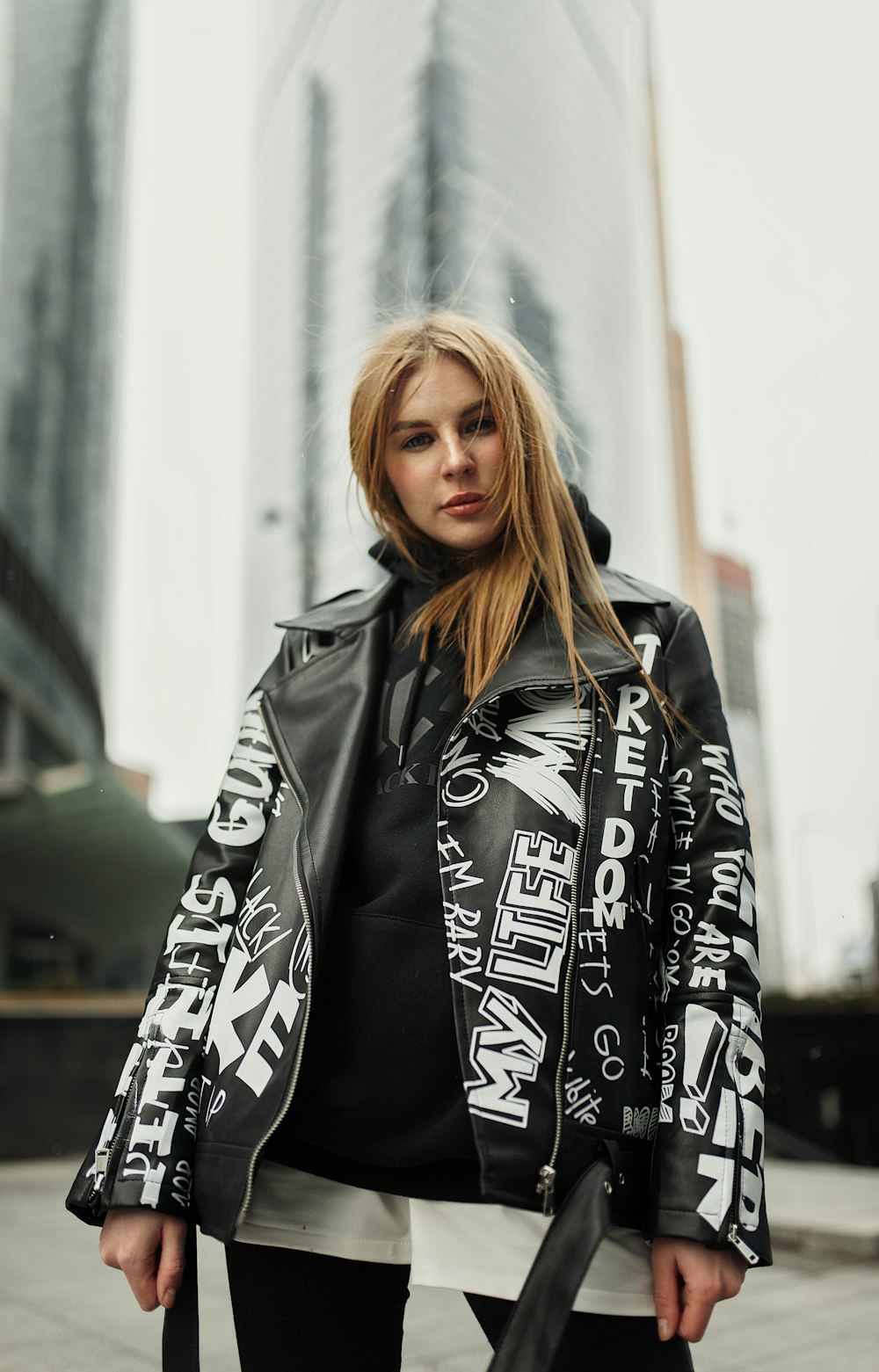 woman in black and white floral coat standing near white wall