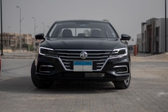 A sleek black luxury sedan parked in front of a modern city skyline.
