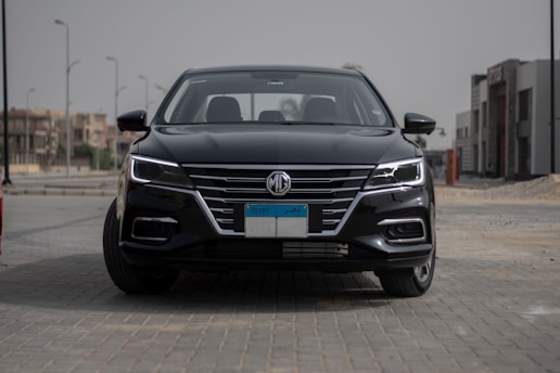 A sleek black luxury sedan parked in front of a modern city skyline.