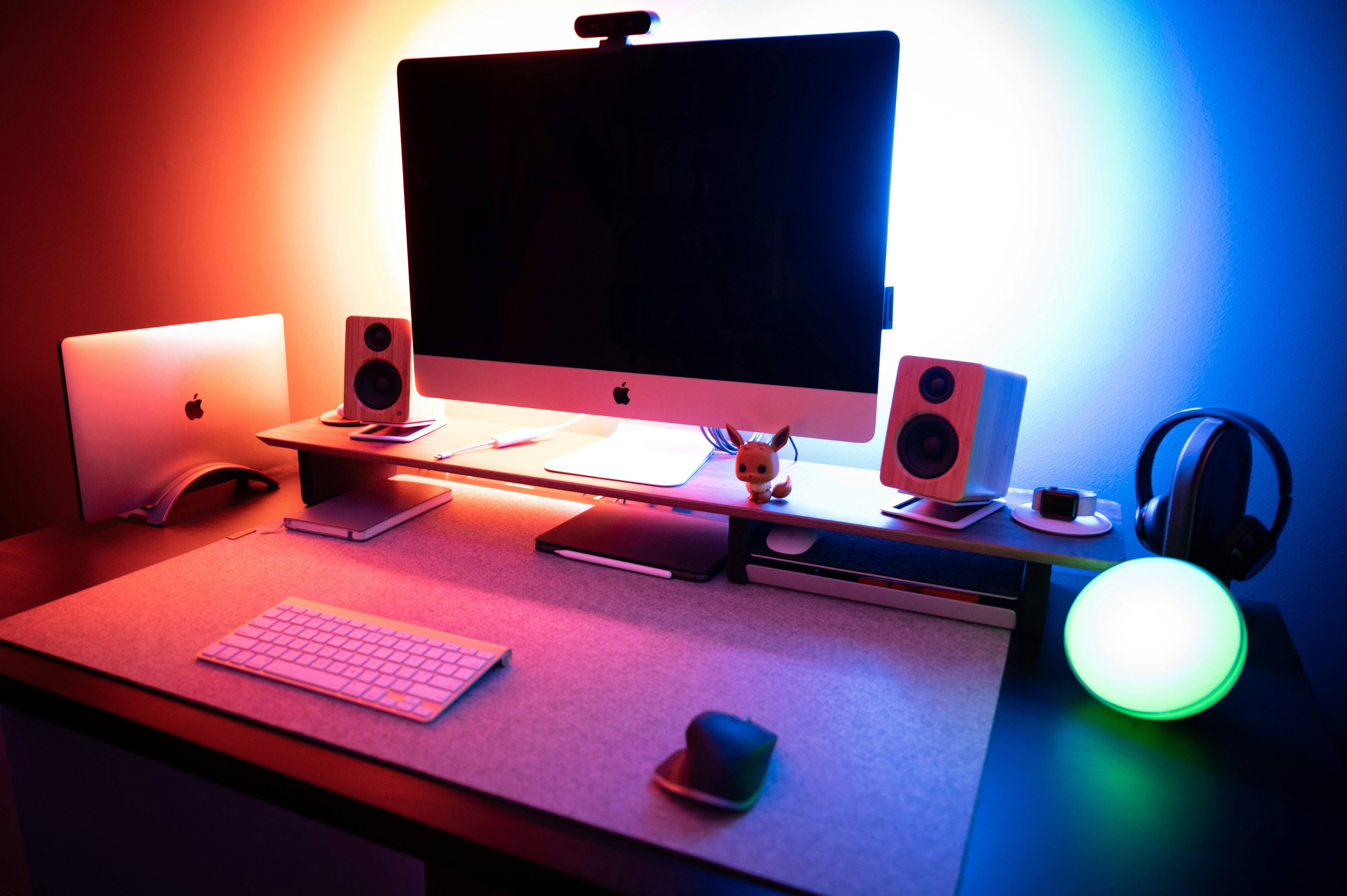 MacBook Pro open on dark desk with ambient glow and minimal studio setup
