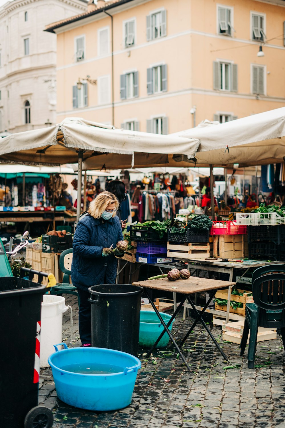 woman in blue jacket standing near brown table during daytime