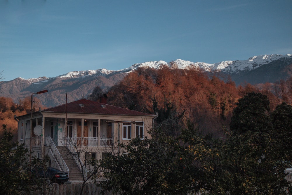 brown and white house near green trees and mountain under blue sky during daytime