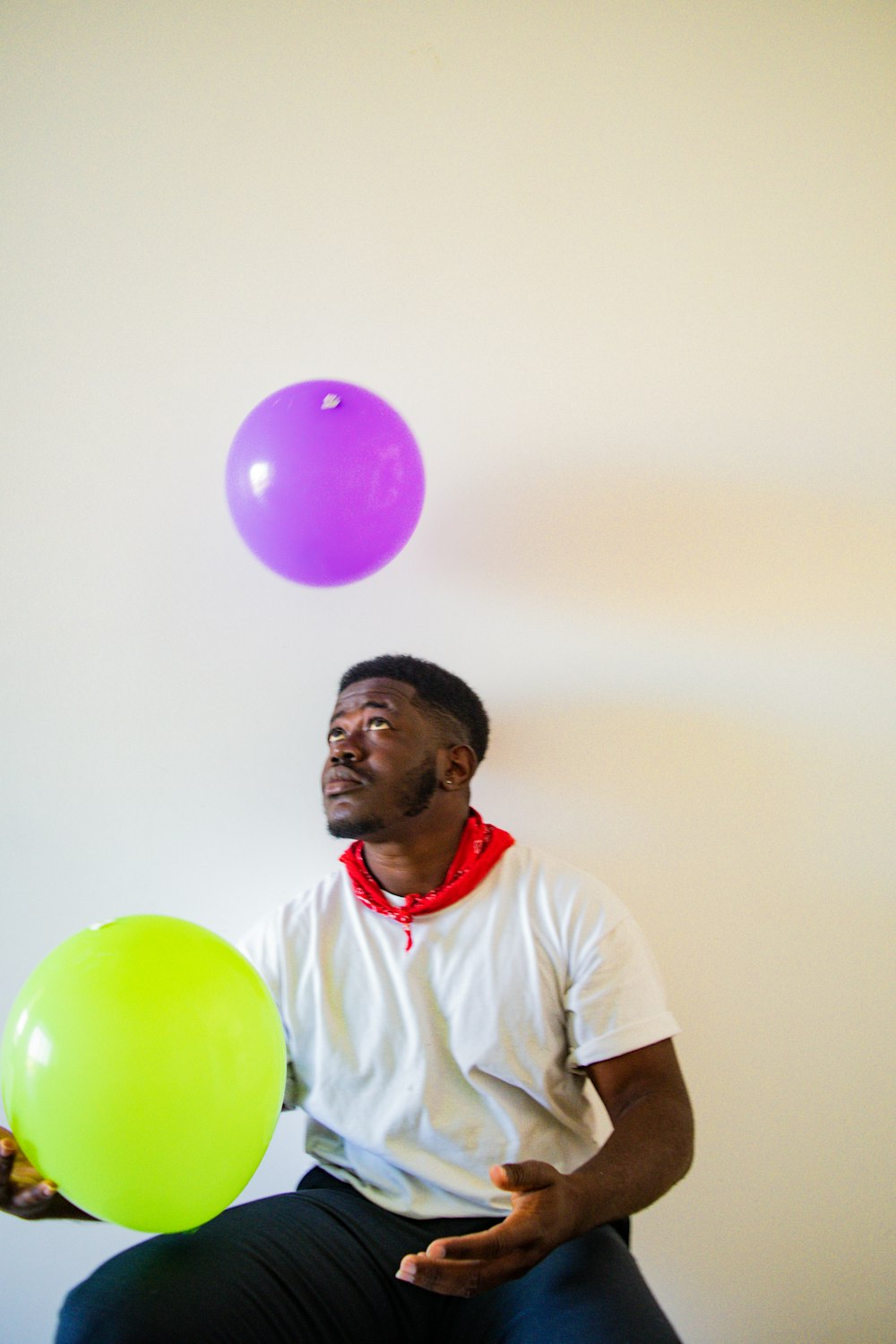 man in white crew neck t-shirt holding green balloon