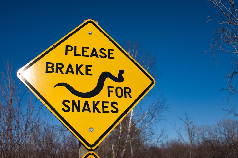 Un cartello giallo che dice per favore frena per i serpenti