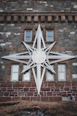Metal star wall decor with a rustic finish hanging against a textured wall.