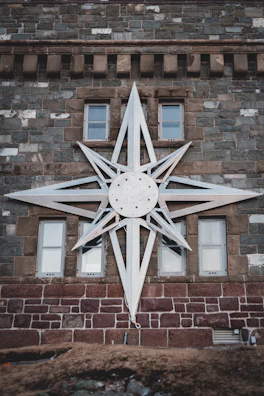 Metal star wall decor with a rustic finish hanging against a textured wall.