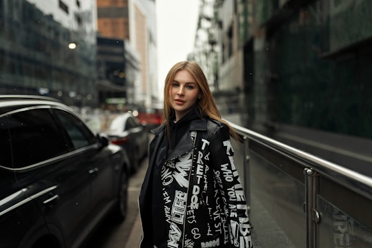 A stylish young woman wearing a simple silver necklace and earrings, walking confidently through a bustling city street.