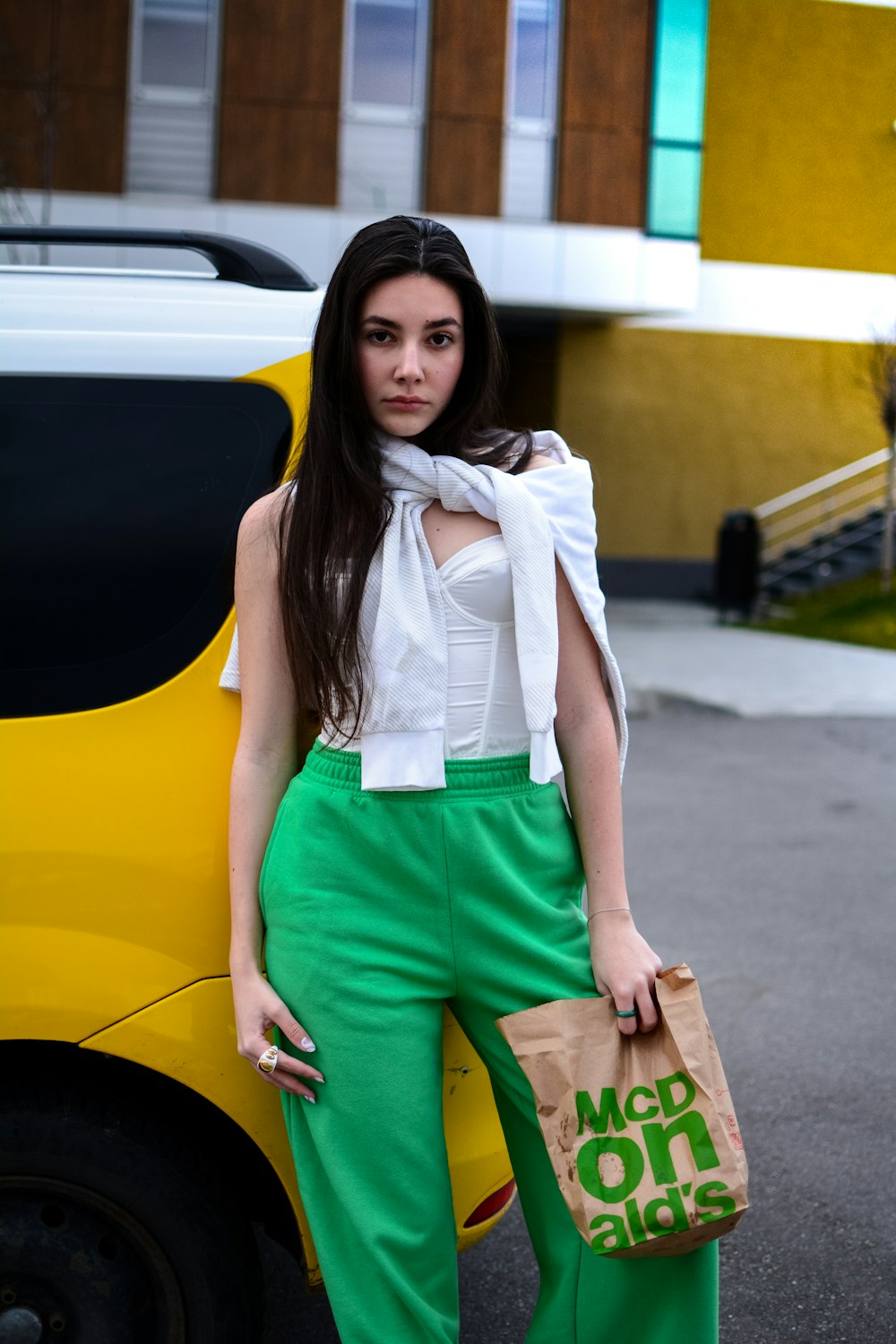 woman in white shirt and green shorts standing beside yellow car