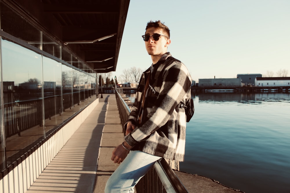 man in black and white checkered dress shirt standing on bridge during daytime