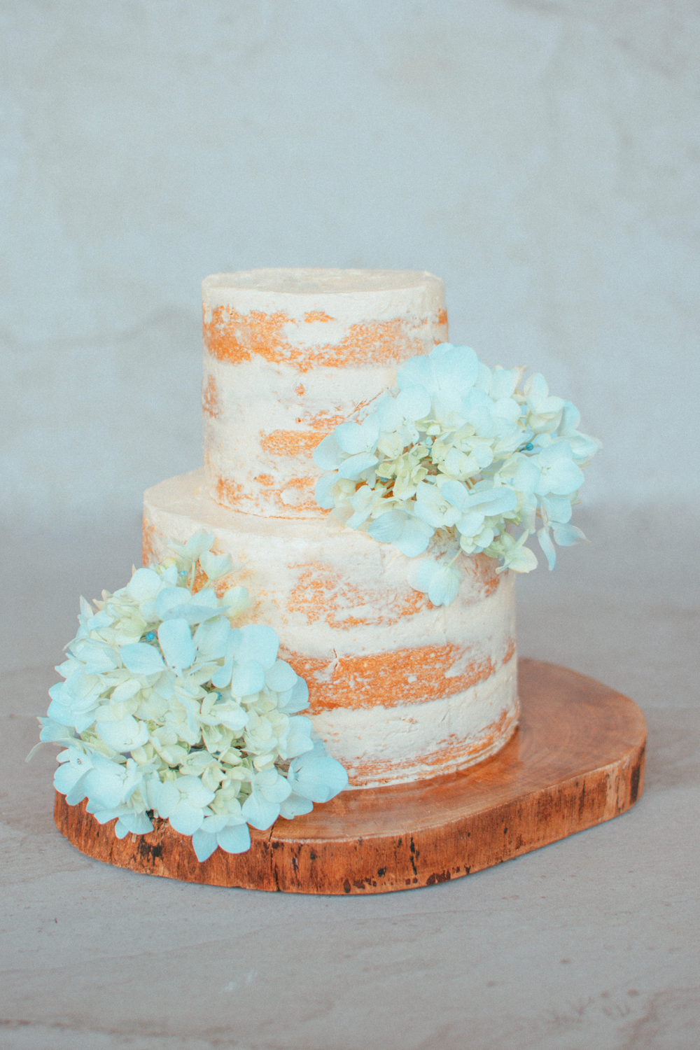 Pastel de 3 capas con flores blancas sobre mesa de madera marrón