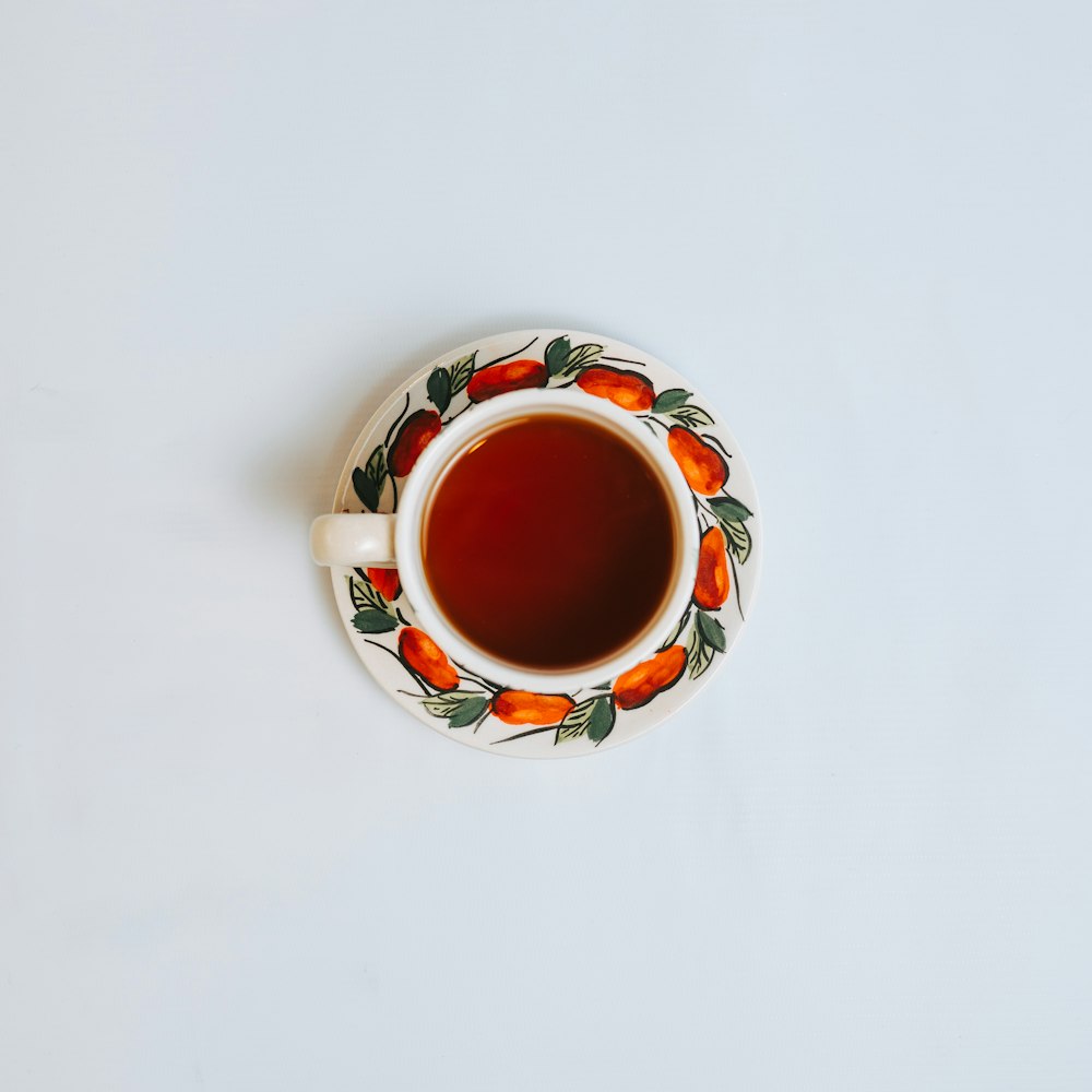 white red and green ceramic mug with brown liquid