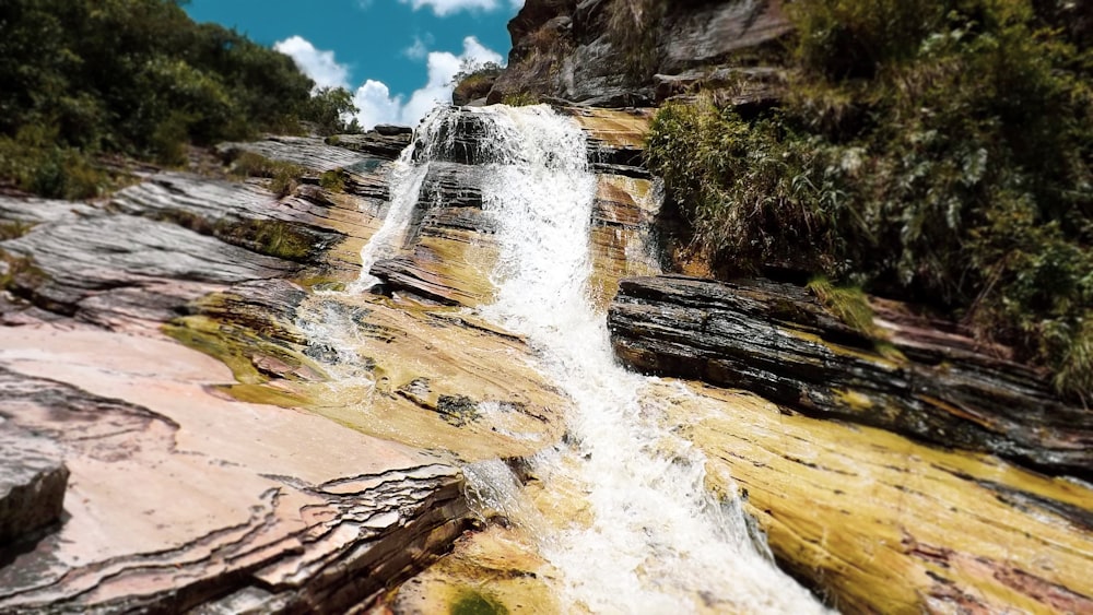 waterfalls on brown rocky mountain under blue sky during daytime