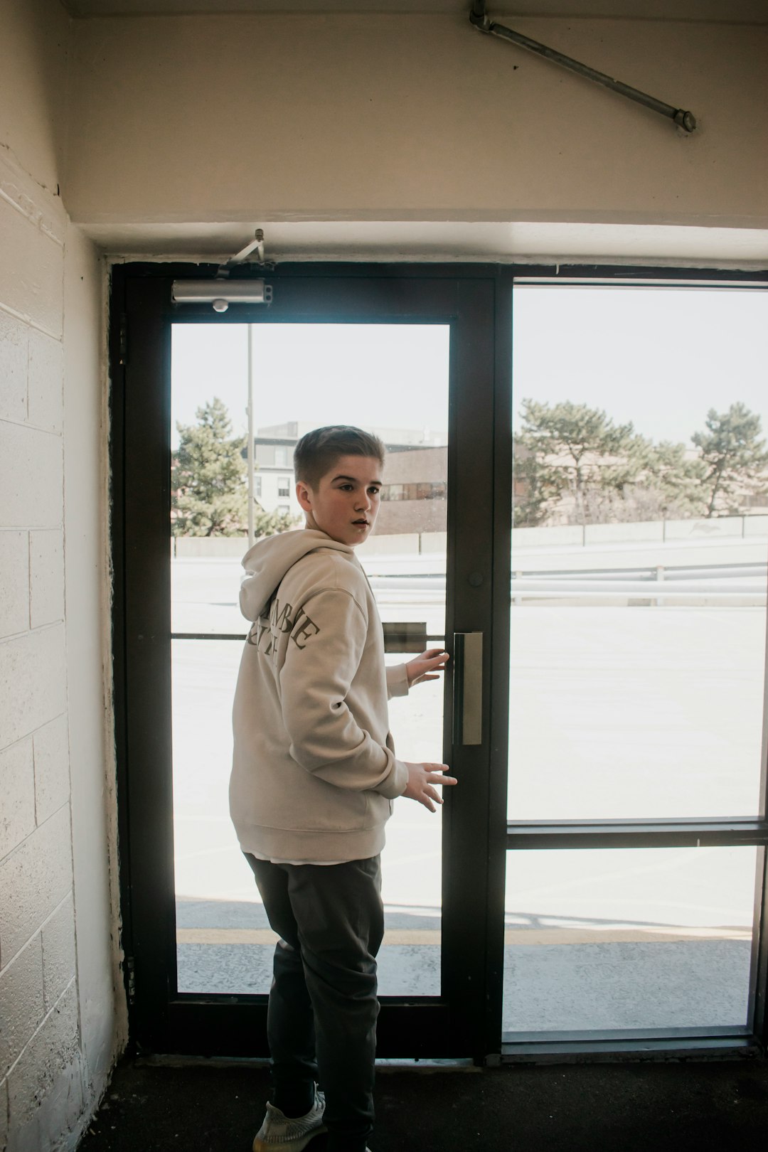 woman in beige sweater standing near glass window