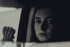 Black and white artistic portrait of a bride looking thoughtfully out a window.