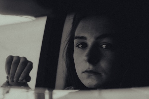 A candid portrait of a person lost in thought, illuminated by soft window light.