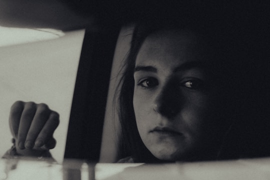 A serene portrait of a person lost in thought by a window with natural light.
