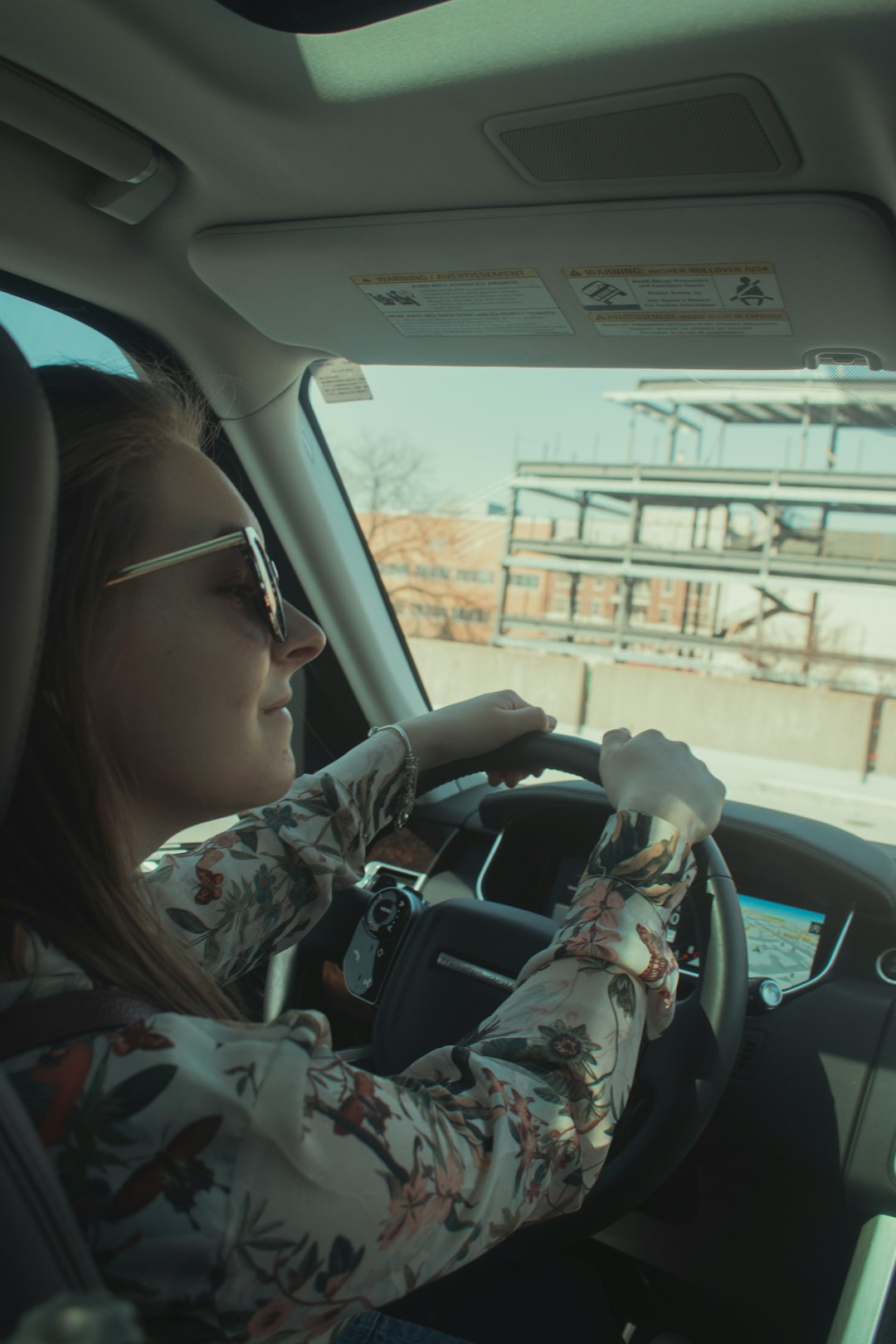 woman in gray and white camouflage jacket driving car during daytime